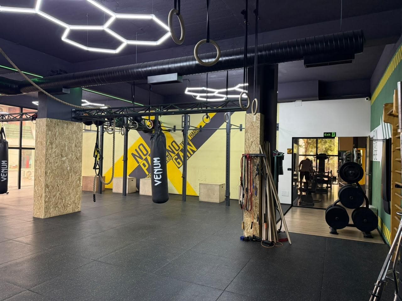Gymnastic rings and a hanging punching bag against the training floor mural at My Fitness